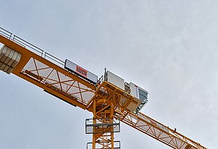 Gelber Baukran mit dem Logo von Wolfer & Goebel über den Dächern von Stuttgart.