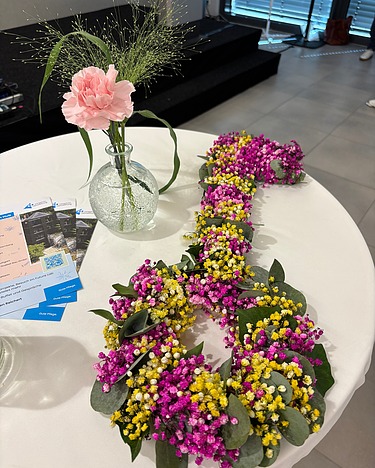 Bunter Blumenflyer auf einem Tisch im Innovation Hub der Evangelischen Heimstiftung in Stuttgart. Daneben stehen Informationsflyer zur Einweihungsveranstaltung und zum Future Lab.