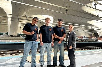 Bild von Azubis und Ausbildungskoordinatorin auf der Baustelle Stuttgart 21. Im Hintergrund sind die Gleisen zu sehen.